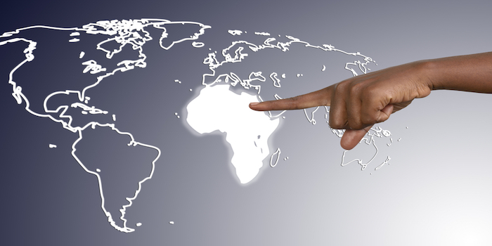 A hand pointing to Africa on a world map